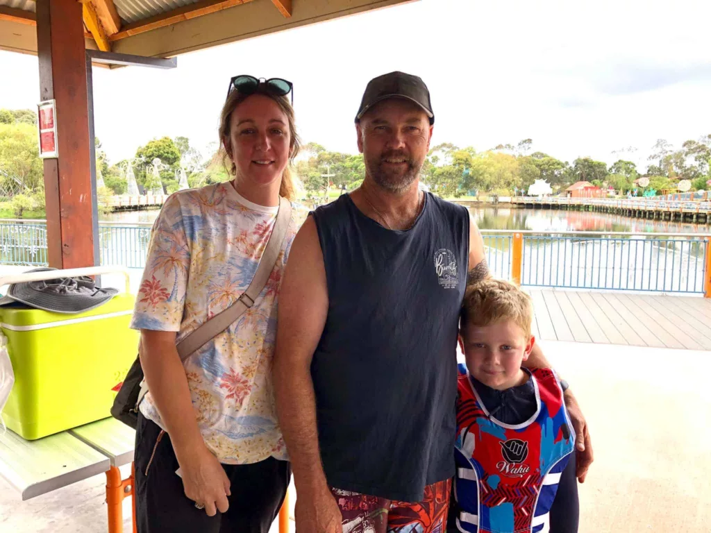 Family of two adults and a child smiling at the camera