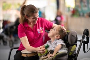 A nurse is helping a young boy play maracas and drums. He is smiling and enjoying himself.