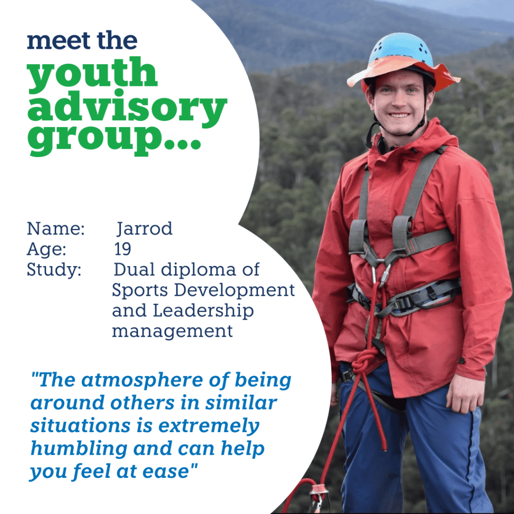 Jarrod, a young male adult is standing outdoors wearing hiking clothing and hat. He is smiling at the camera.