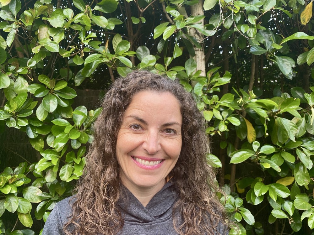 Brunette women smiling at camera with leaves in background